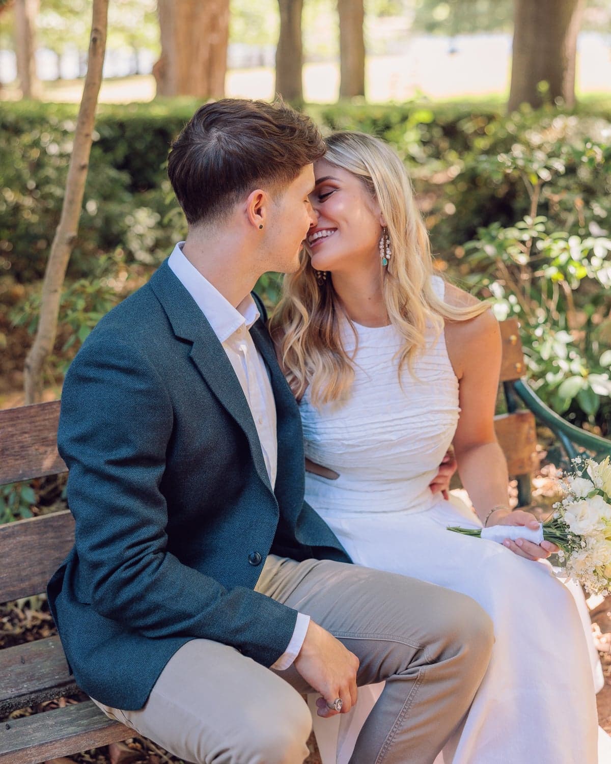 Couple laughing together on a bench during wedding photography at Nara Peace Gardens, Canberra.