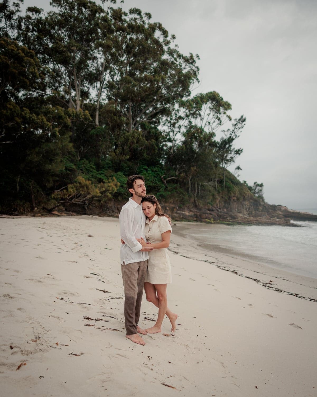 Newly engaged couple embracing barefoot on the beach during proposal photography at Jervis Bay NSW by Alejandro Martin.